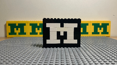 Picture of yellow lego figure with green M